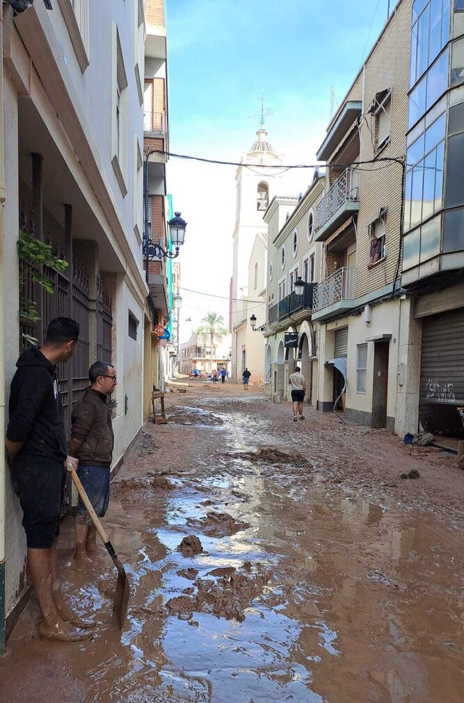 Voluntarios limpiando el fango junto a la iglesia